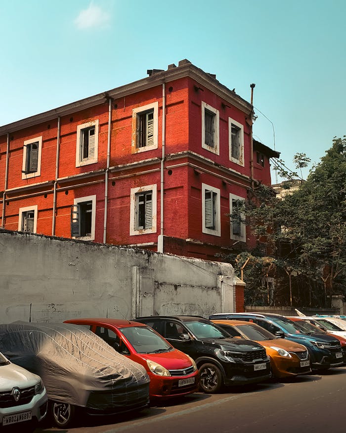 A charming red brick building with cars parked in front, bright sky above.