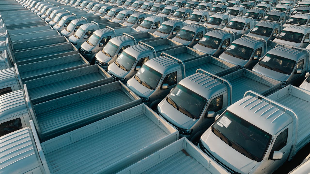Aerial shot of multiple silver pickup trucks aligned in rows, showcasing symmetry and industrial production.